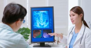 A female doctor explained x-ray film on the computer to a male patient at the clinic The patient is asking the doctor What to do if you experience colon pain over time